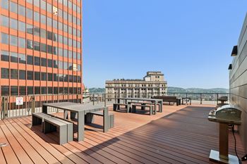 A wooden deck with benches and a table with a building in the background.
